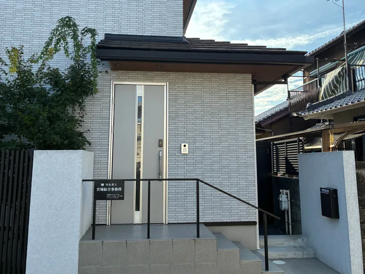 司法書士宮城綜合事務所の外観。白いタイル張りの建物で、門柱の左手に事務所の看板があります